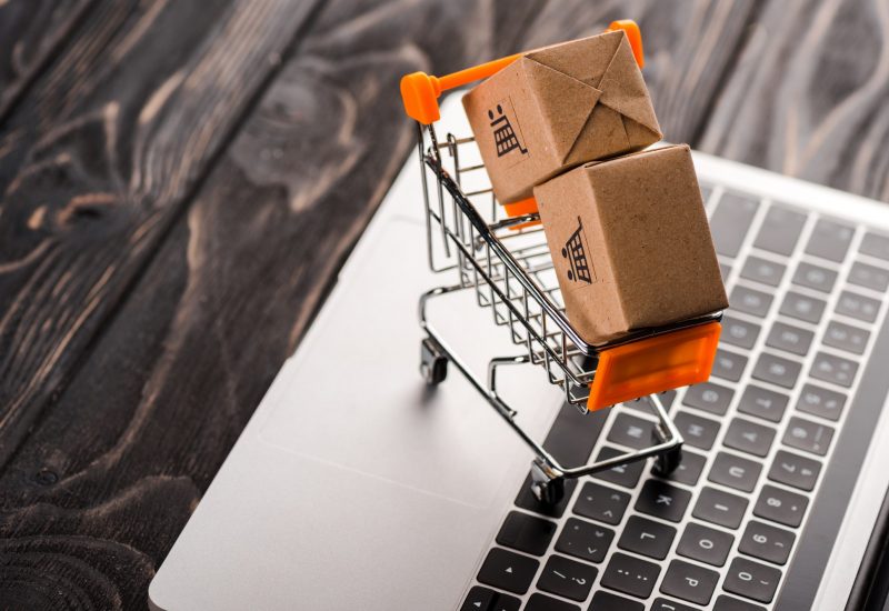 toy boxes in small shopping cart on laptop, e-commerce concept