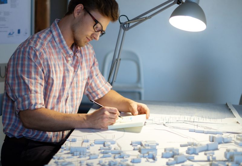 Young architect working on drawing table in architect studio.
